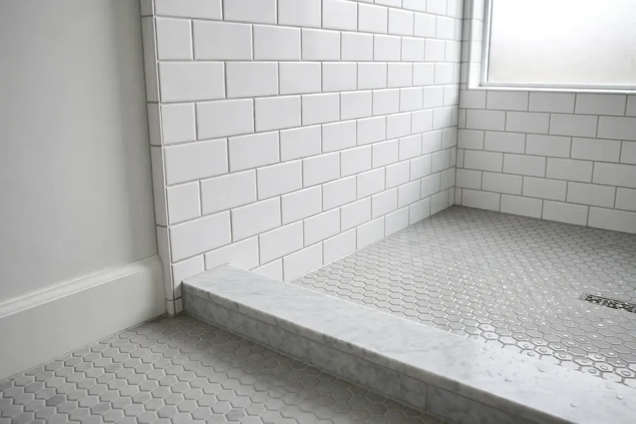 Shower wall tile and floor tile meeting at a low curb