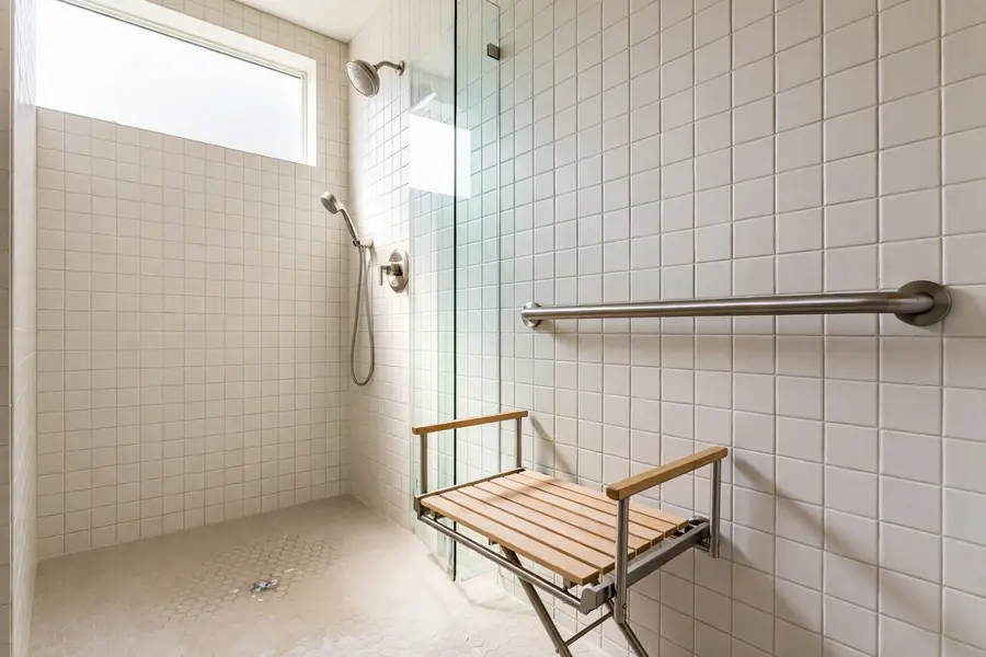 Shower with a metal grab bar and a folding bench seat