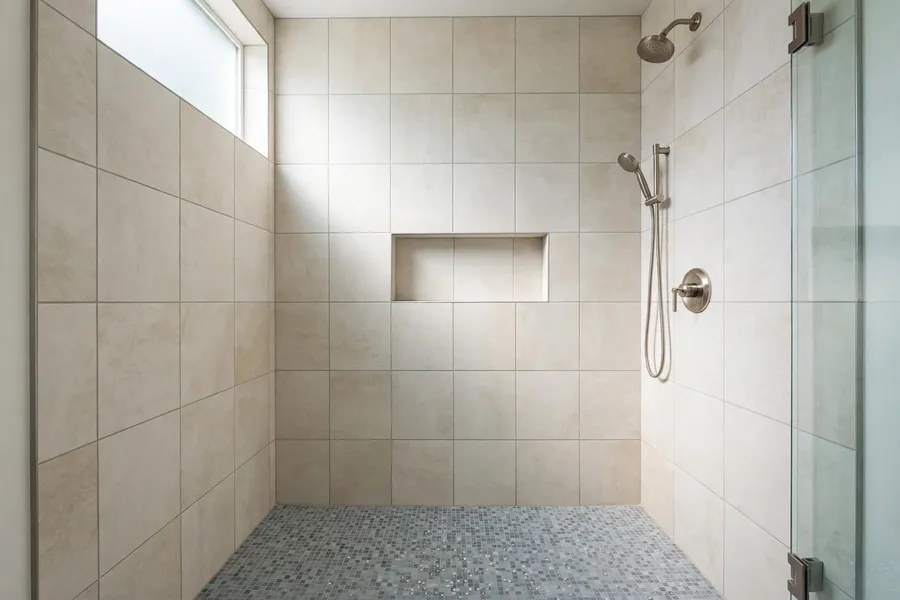 Shower walls in large tile with a small mosaic tile floor