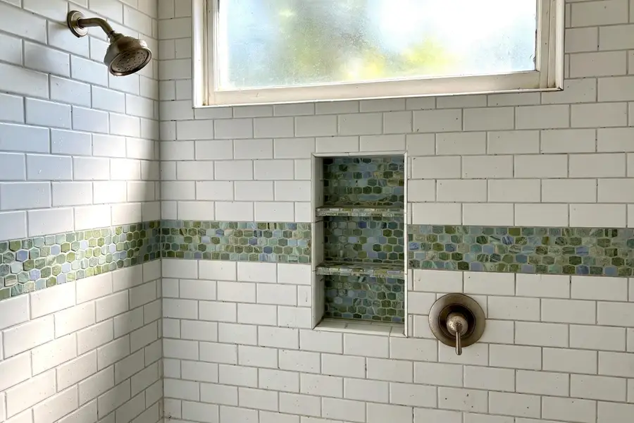 Shower wall with a tiled accent band and a recessed niche