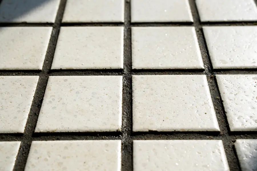 Close-up of dark grout joints between light bathroom floor tiles