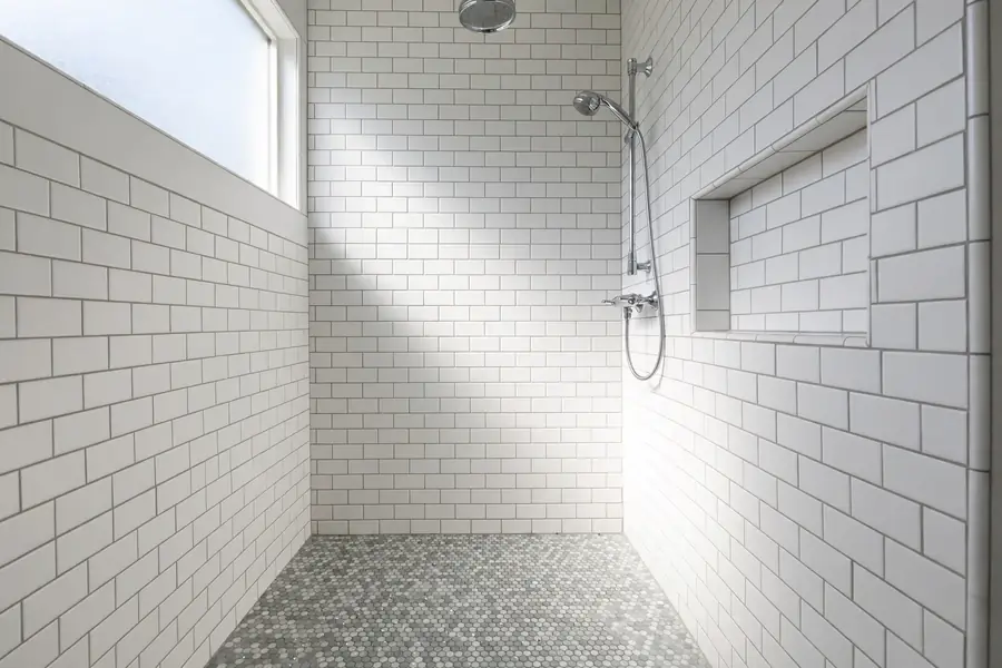 Shower with white subway tile walls and a small mosaic tile floor