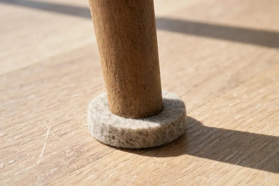Chair leg with a felt pad on a vinyl plank floor