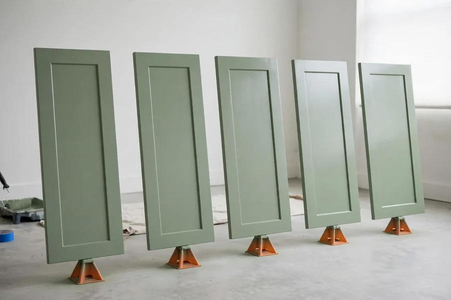 Freshly painted cabinet doors drying upright on small stands, spaced apart and untouched.