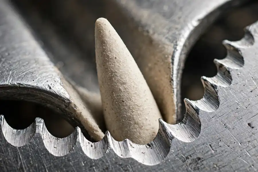 A tapered ceramic rod seated in one gullet of a serrated bread knife blade.